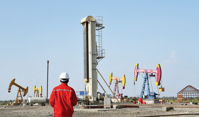 Workers are seen near pumpjacks at a CNPC oil field in Bayingol